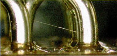 Close-up of shiny silver metal rings over a reflective surface with greenish-brown background