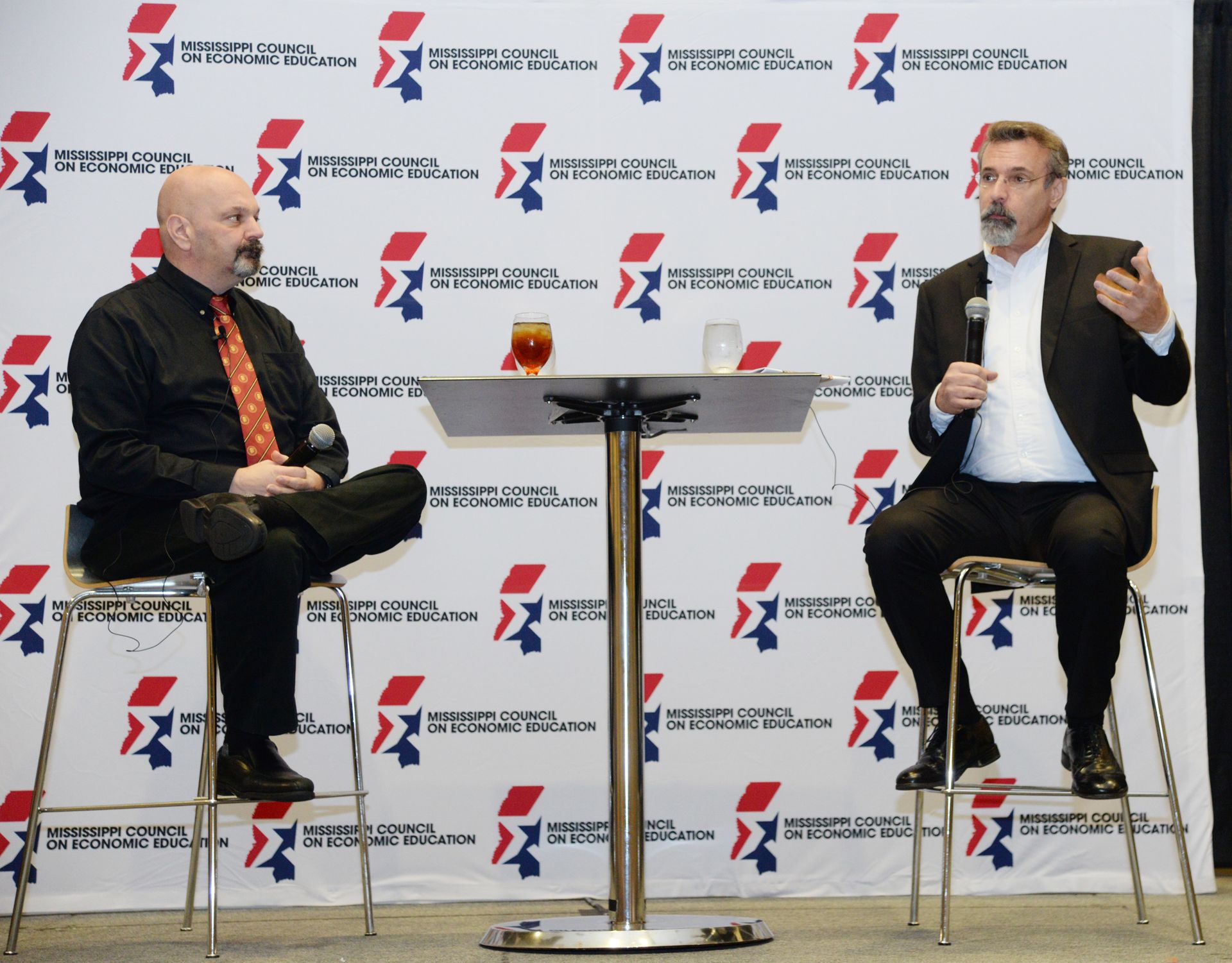 Two men are sitting at a table talking to each other