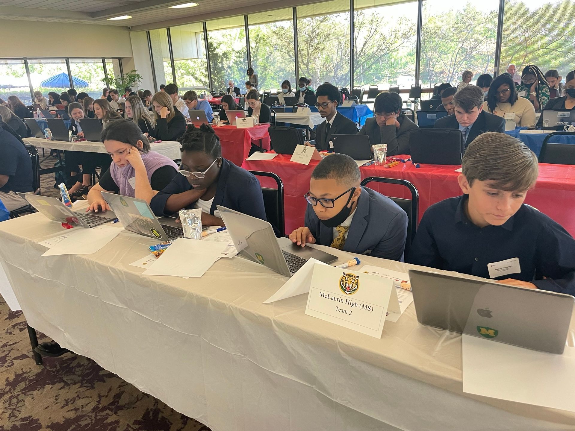 A group of people are sitting at tables with laptops.