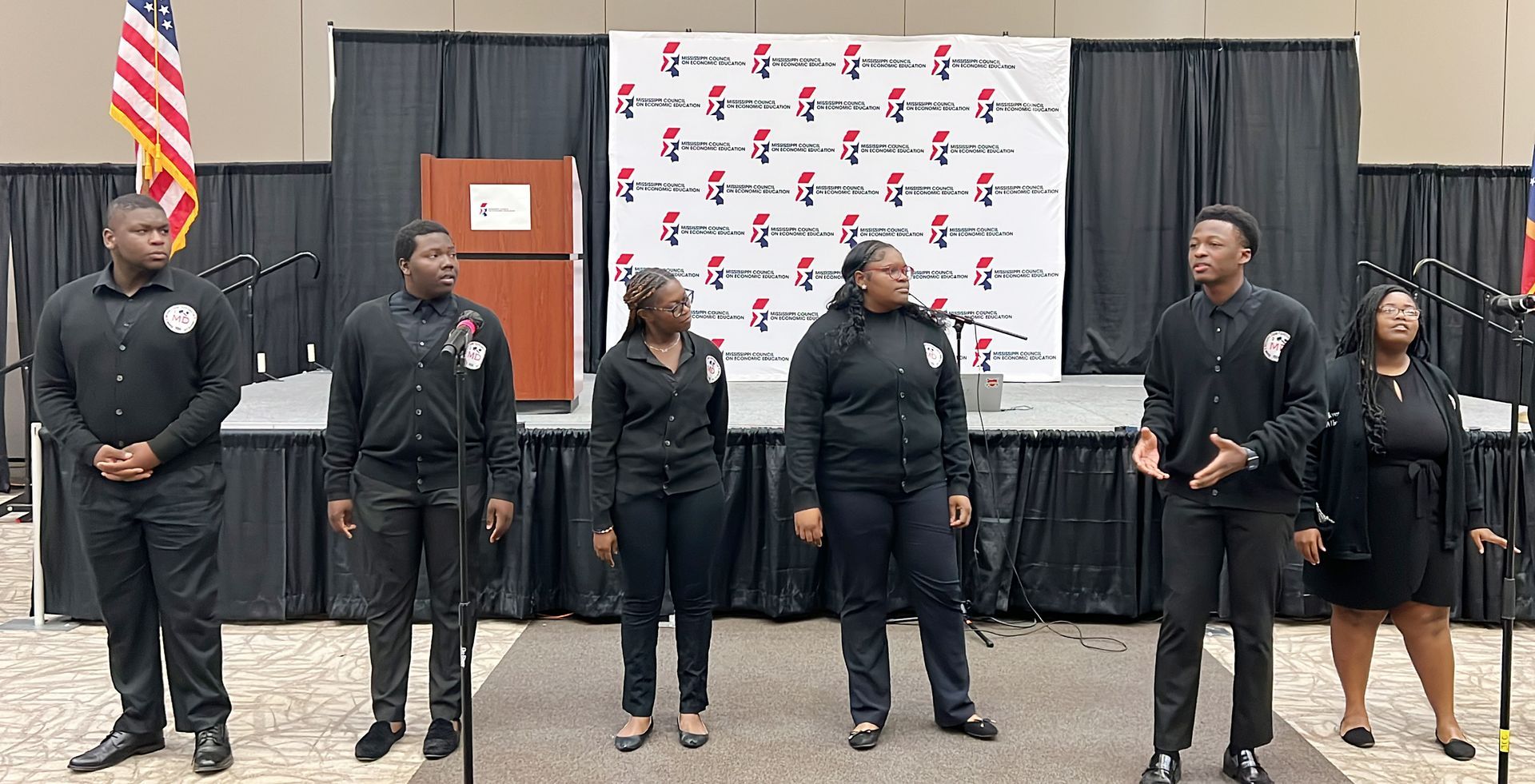 A group of people are standing in front of microphones in a room.
