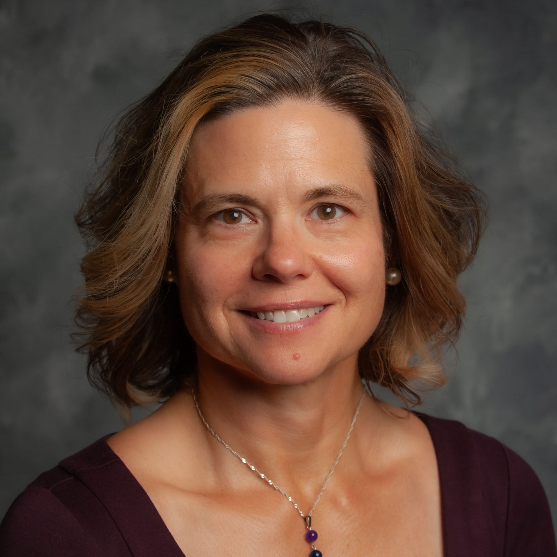 A woman with short hair and hoop earrings is smiling for the camera.