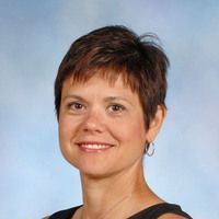 A woman with short hair and hoop earrings is smiling for the camera.