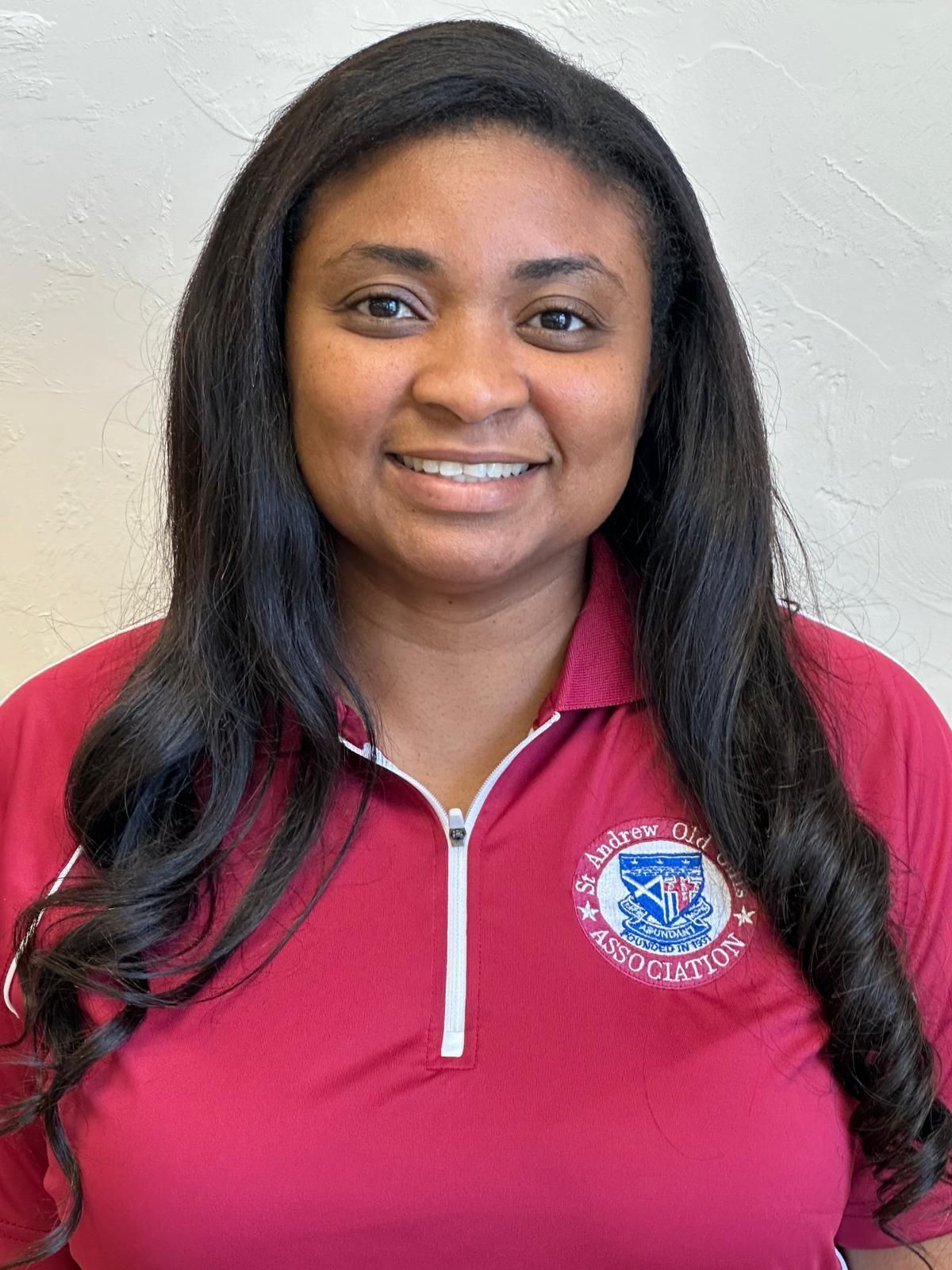 A woman wearing a red polo shirt is smiling for the camera.
