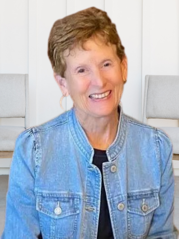 A woman in a denim jacket is smiling for the camera.