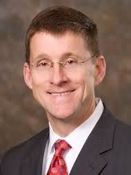 A man in a suit and tie is smiling for the camera.