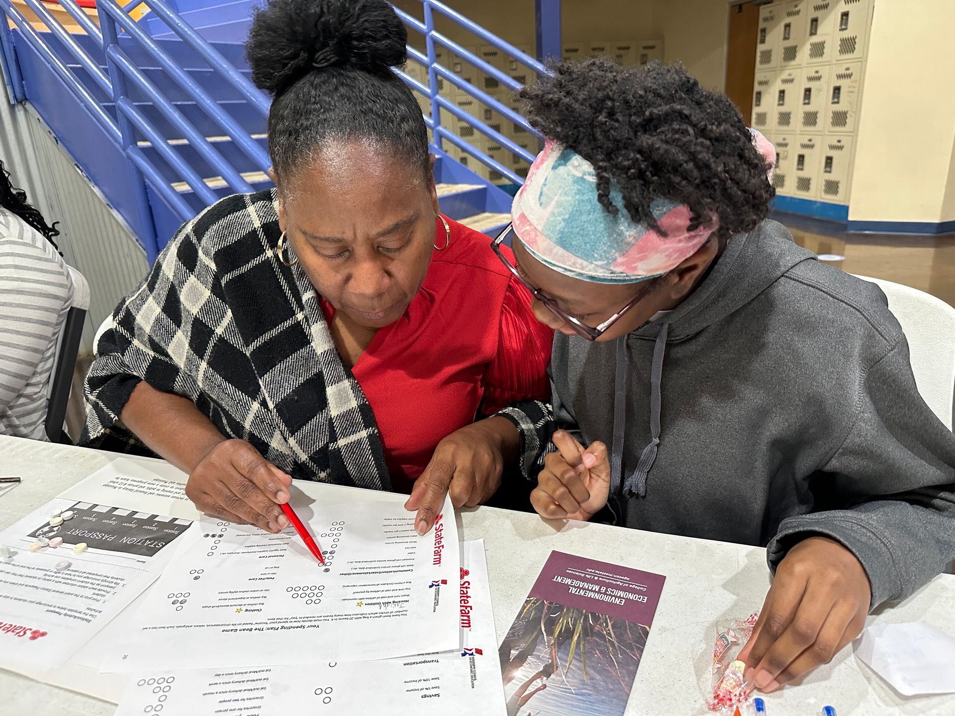 Two women are sitting at a table working on a project.