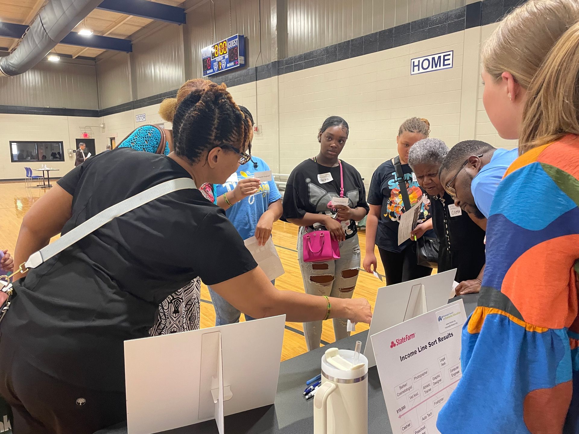 A group of people are standing around a table in a gym.