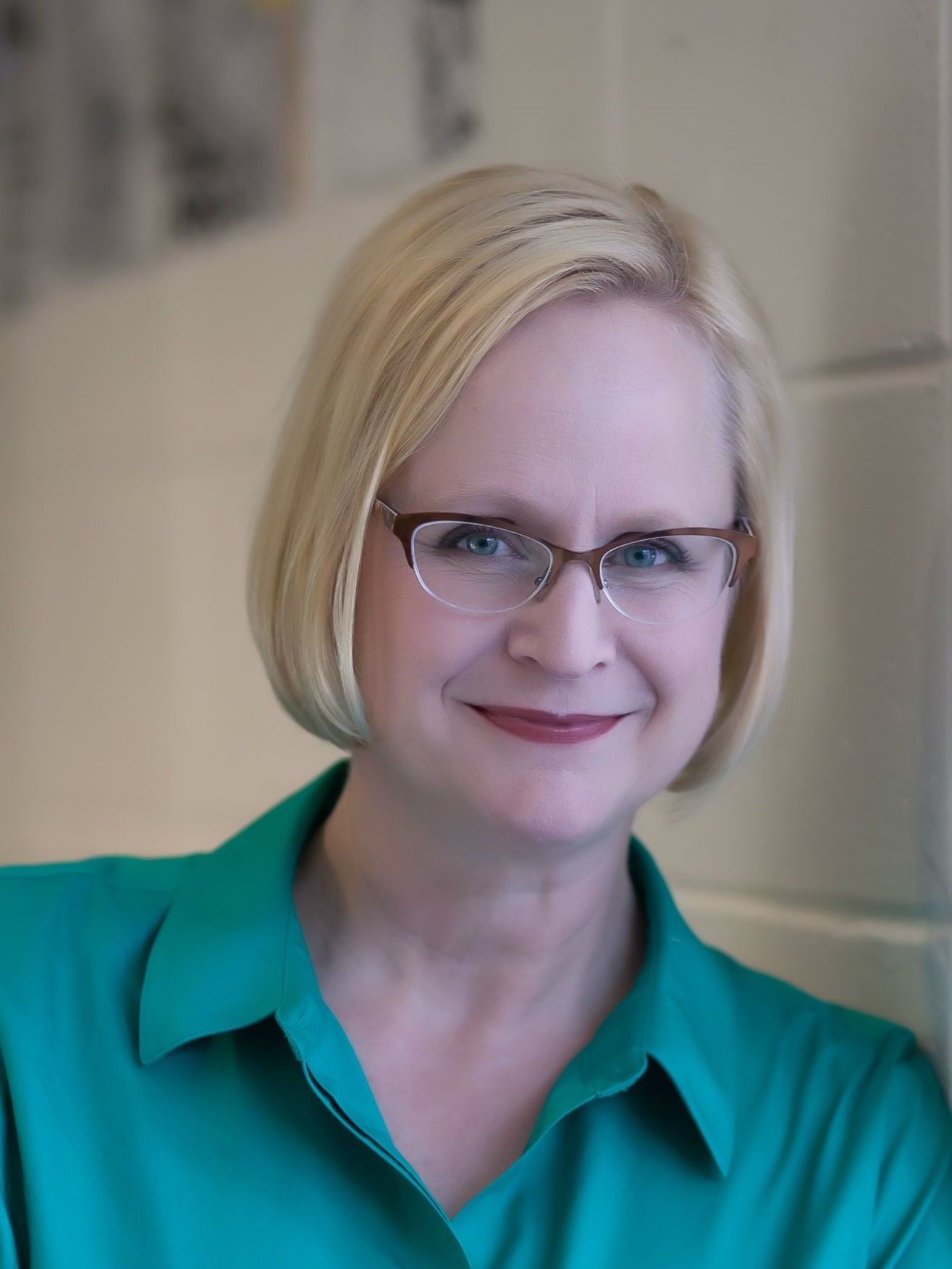 A woman wearing glasses and a green shirt smiles for the camera
