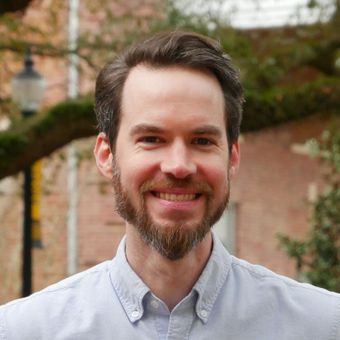 A man with a beard and a blue shirt is smiling for the camera.