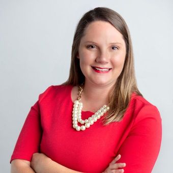 The woman is wearing a red dress and a pearl necklace.