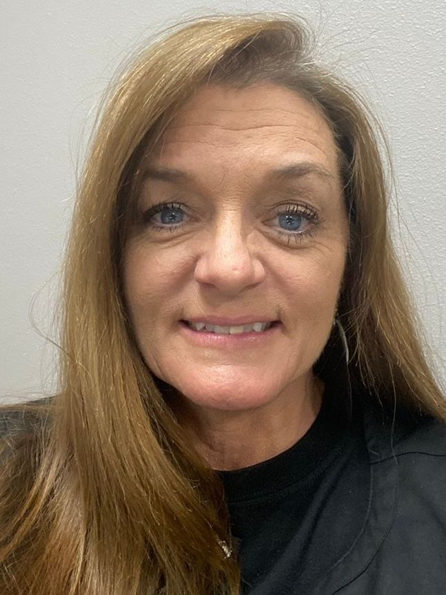A woman with long hair and blue eyes is smiling for the camera.