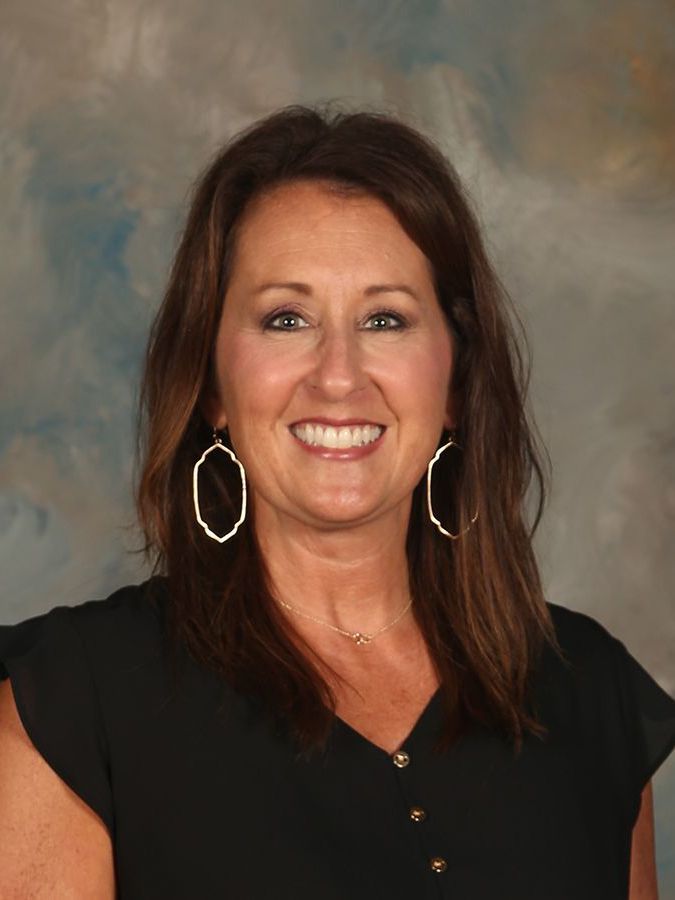 A woman wearing hoop earrings and a black shirt is smiling for the camera.