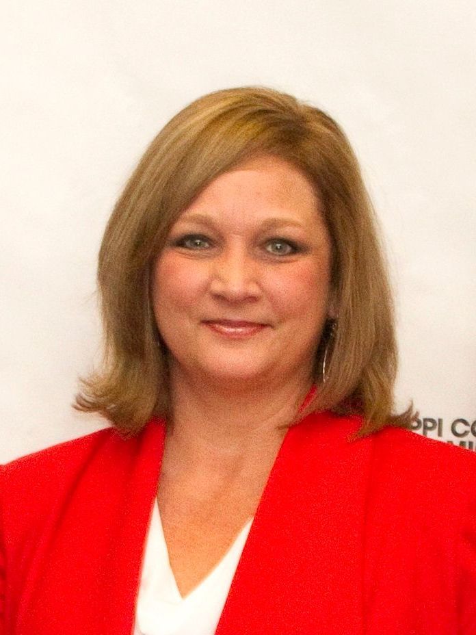 A woman is wearing a red jacket and white shirt