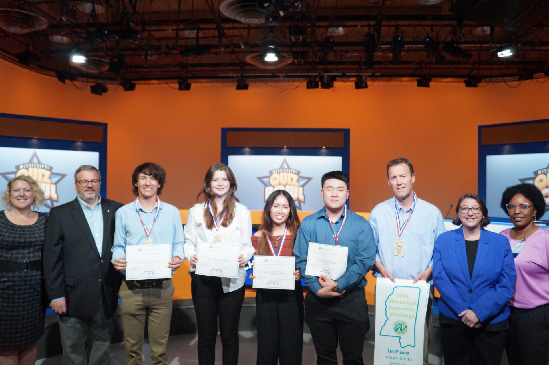 A group of people are posing for a picture in front of an orange wall.