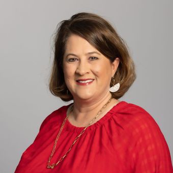 A woman wearing a red shirt is smiling for the camera.