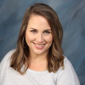 A woman is smiling for the camera in front of a blue background.