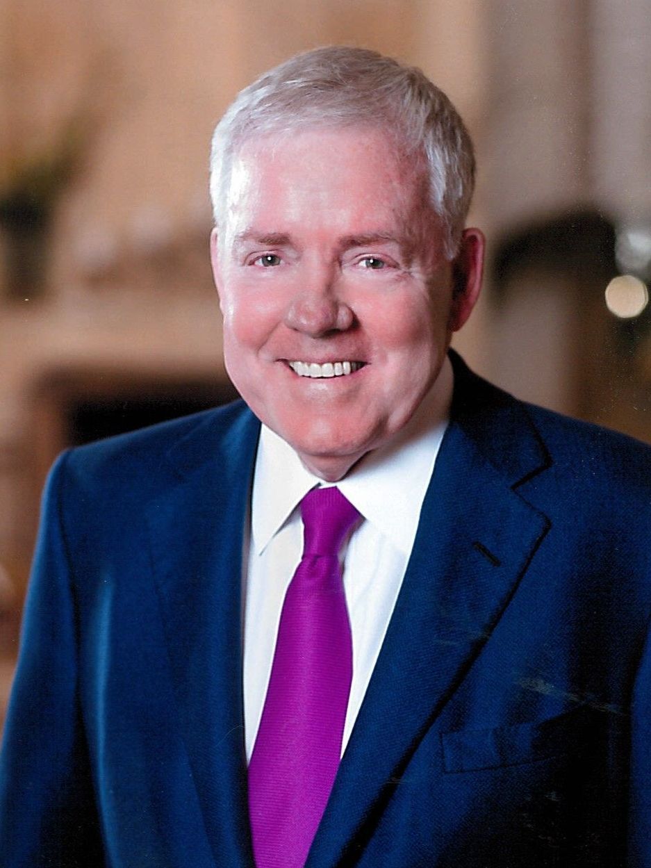 A man in a suit and tie is smiling for the camera