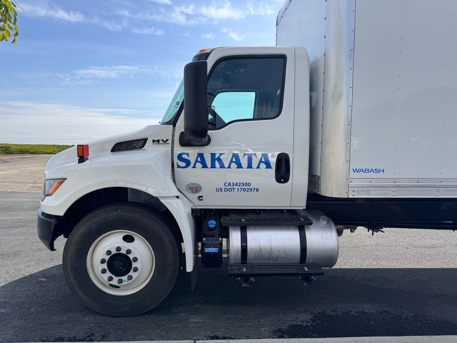 A white sakata truck is parked on the side of the road.