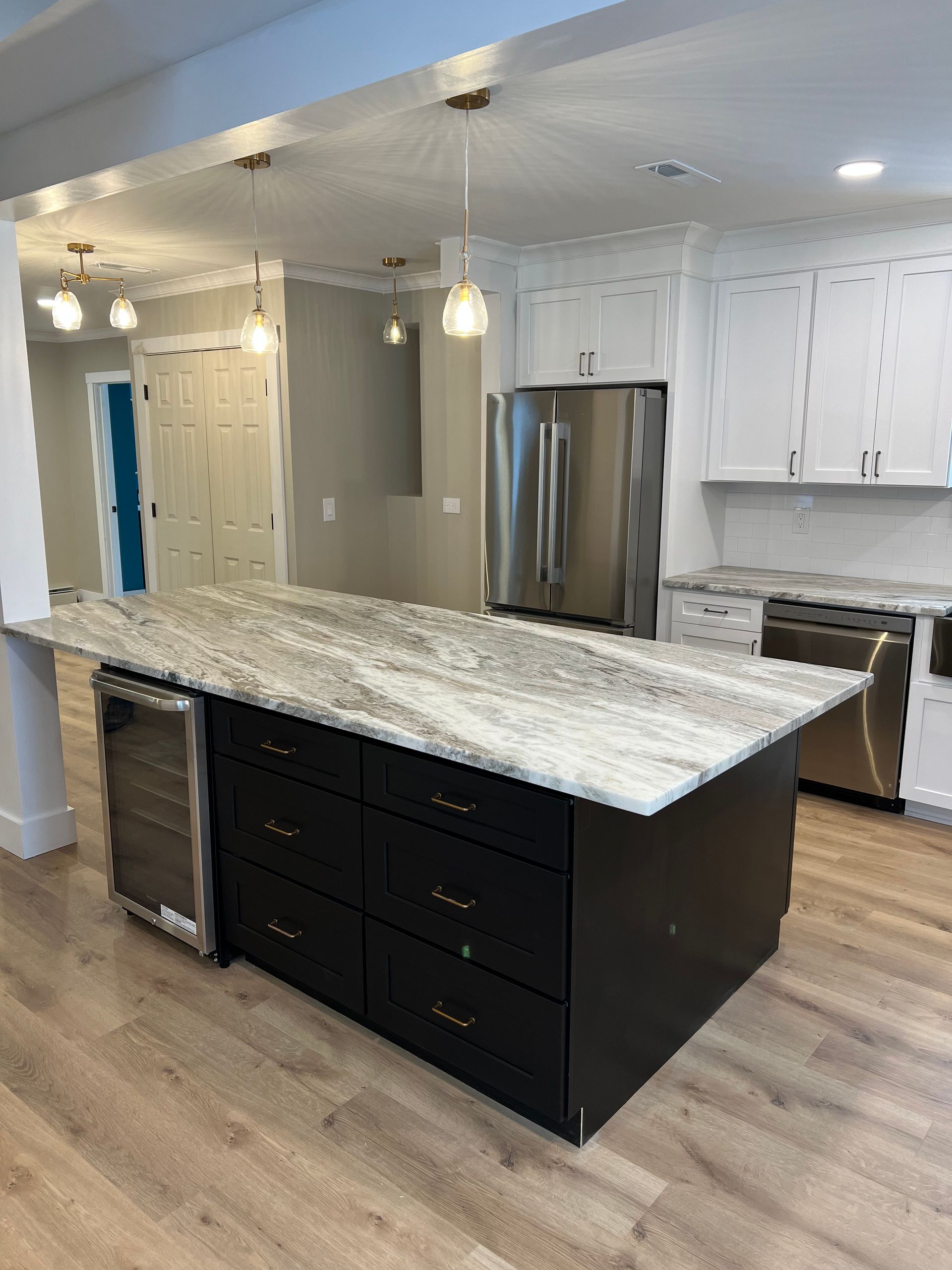 Modern kitchen with black island, white countertops, and stainless steel appliances.