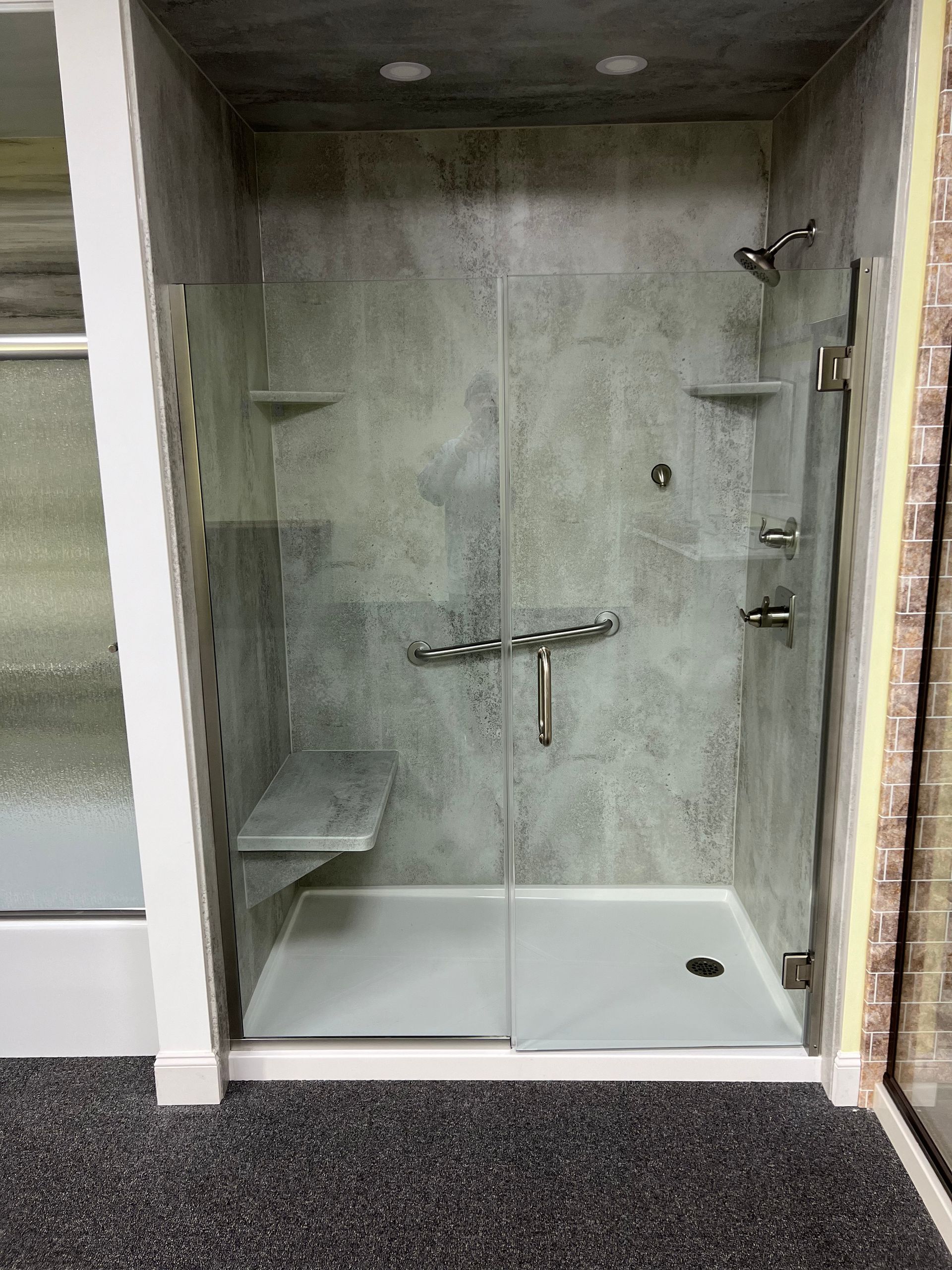 A shower stall with a sliding glass door and a bench.
