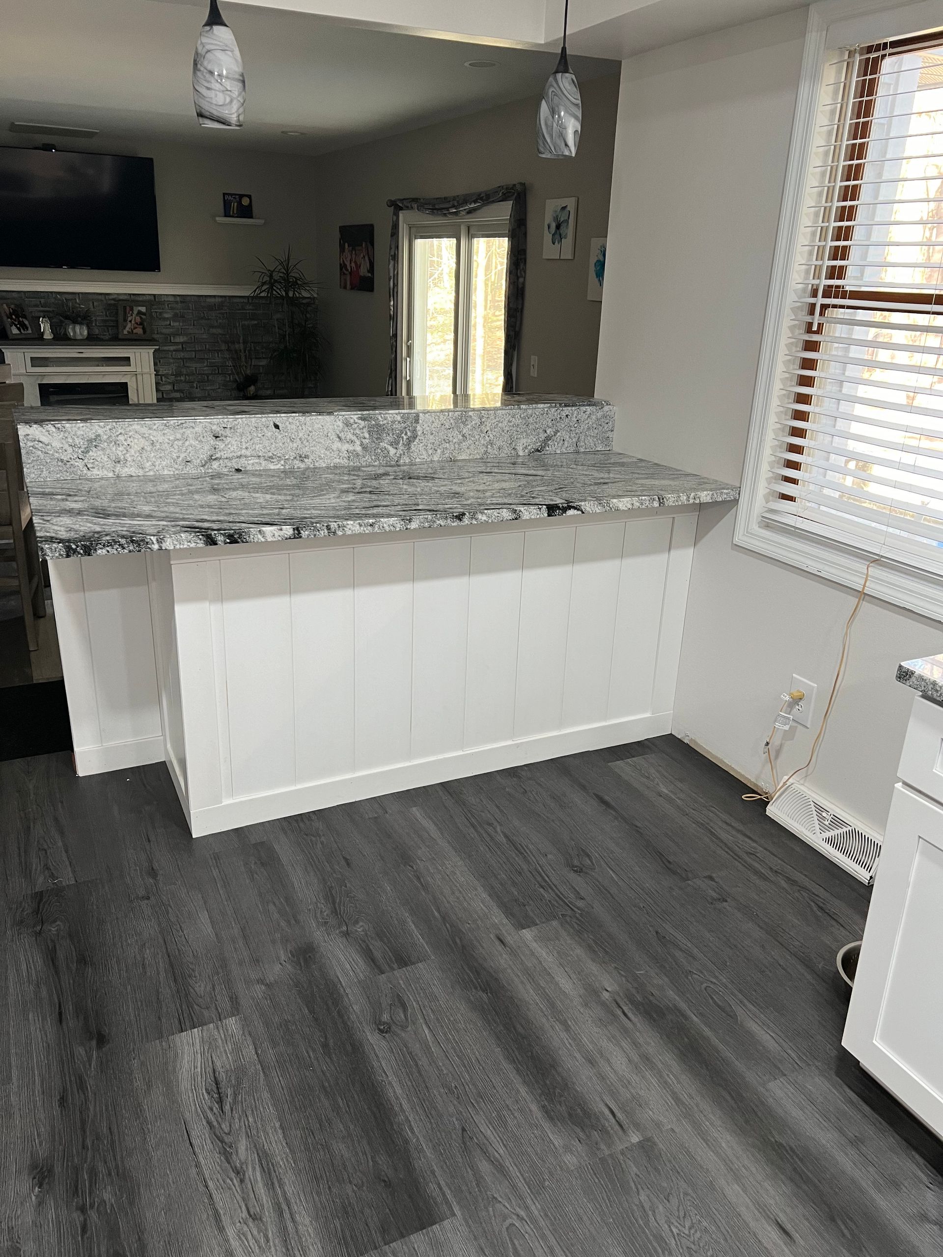 A kitchen with granite counter tops and a gray floor.