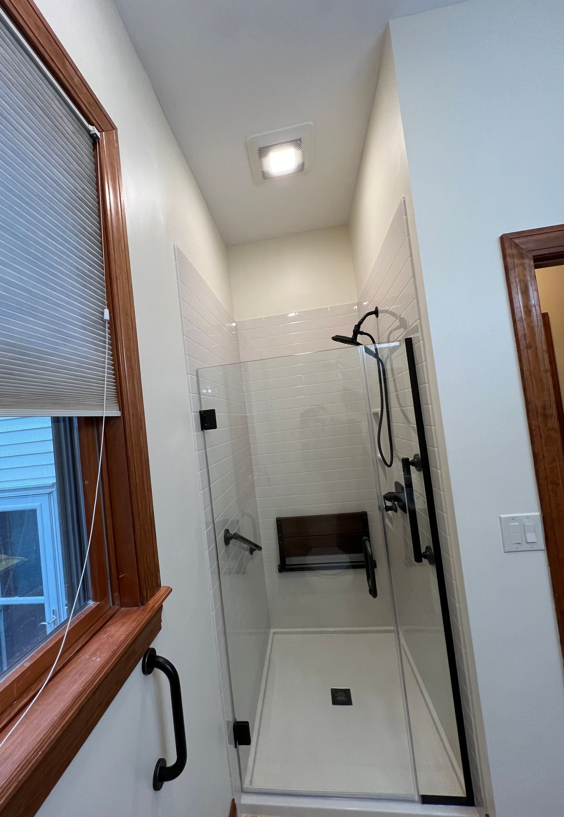 A bathroom with a walk in shower and a window.