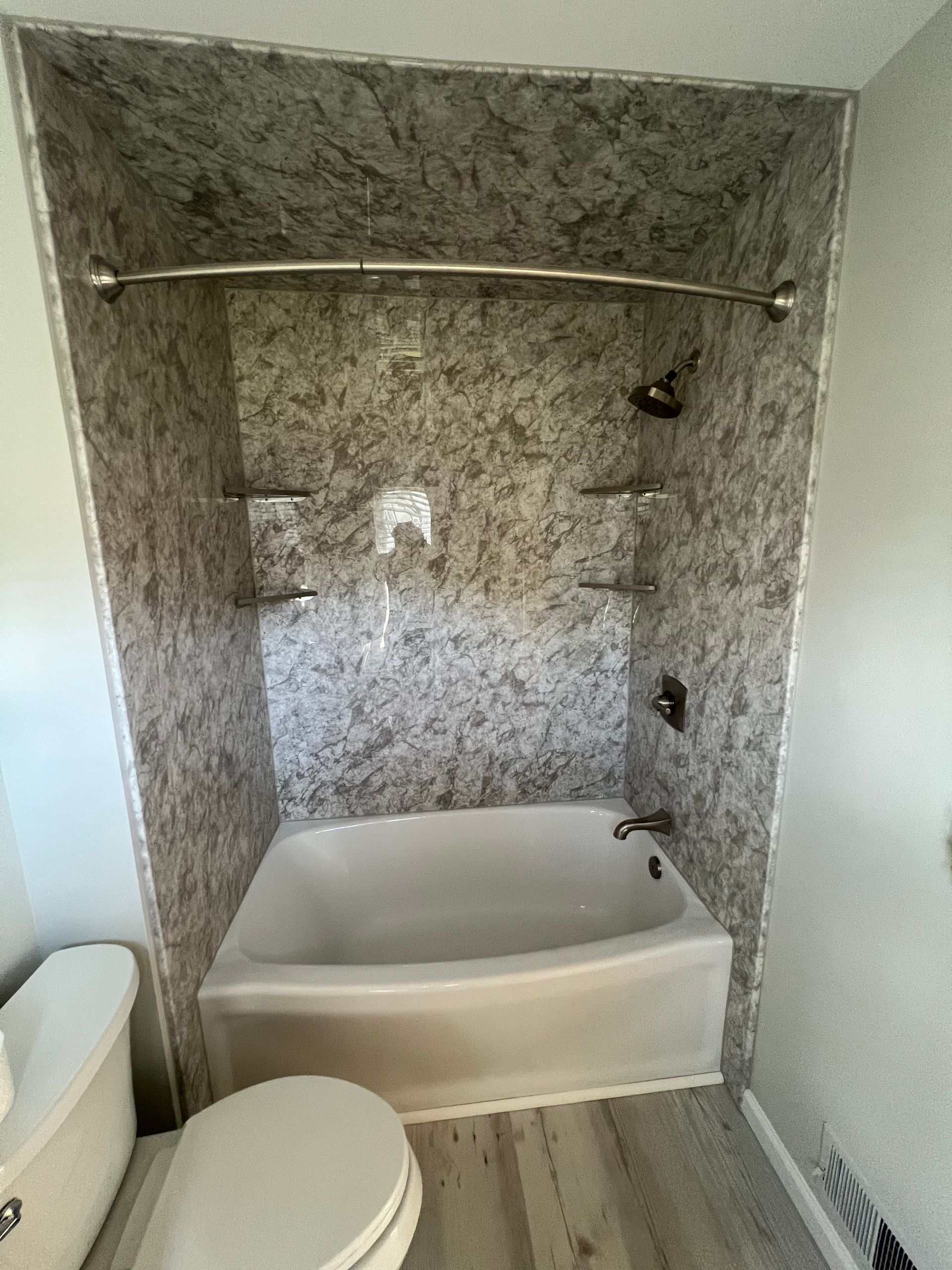 A bathroom with a tub , toilet and shower.