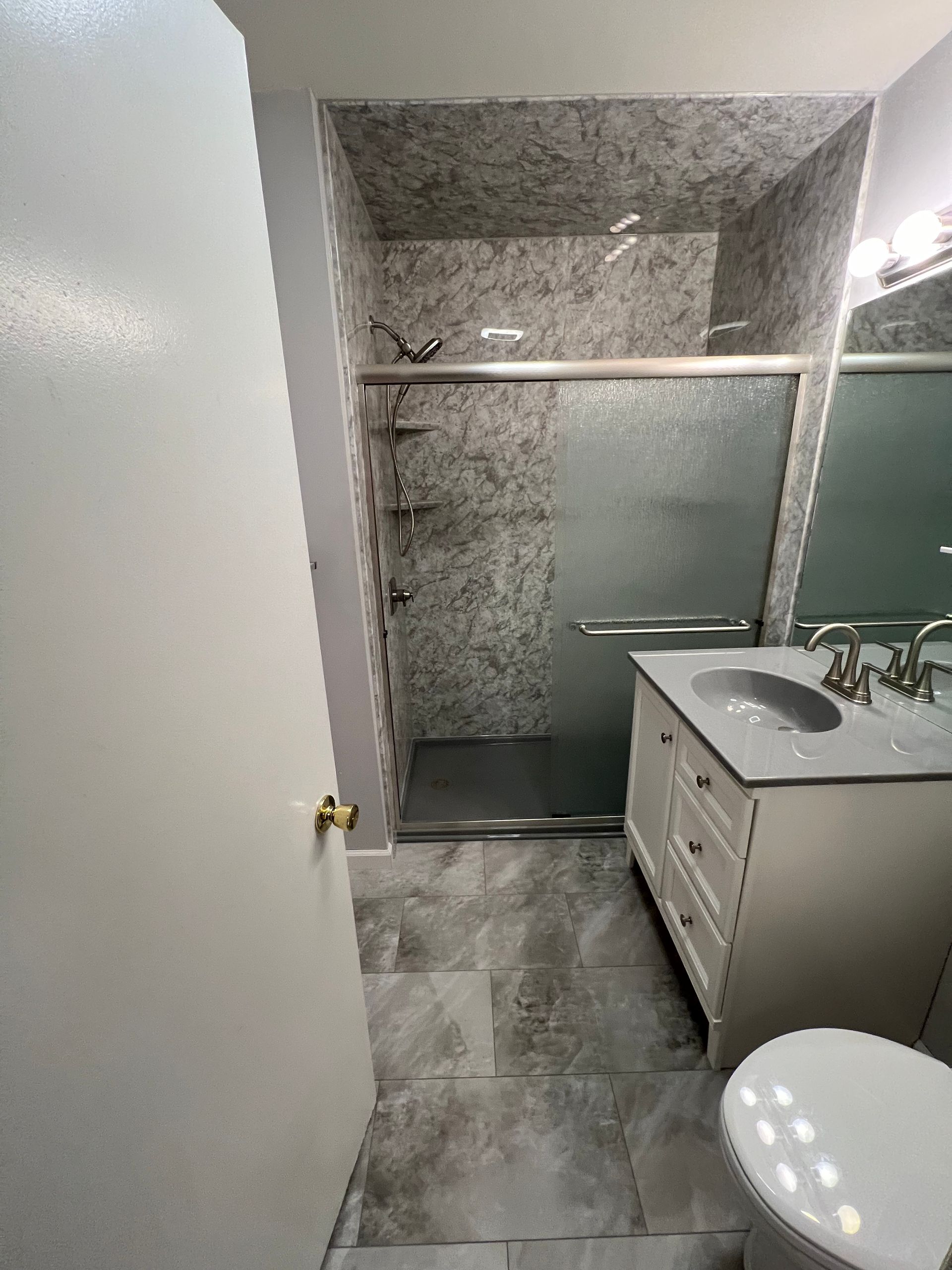 A bathroom with a sink , toilet and shower.