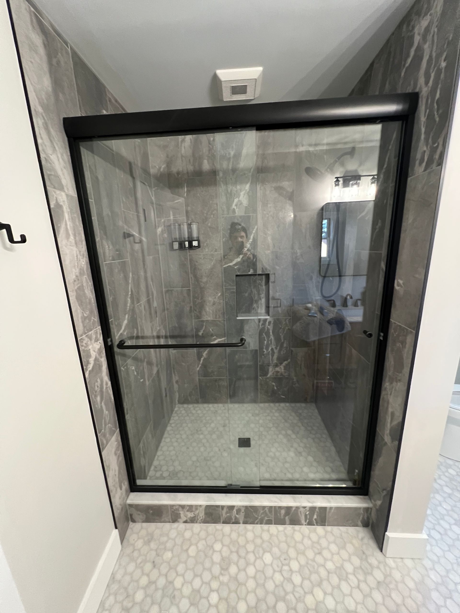 A bathroom with a sliding glass shower door.