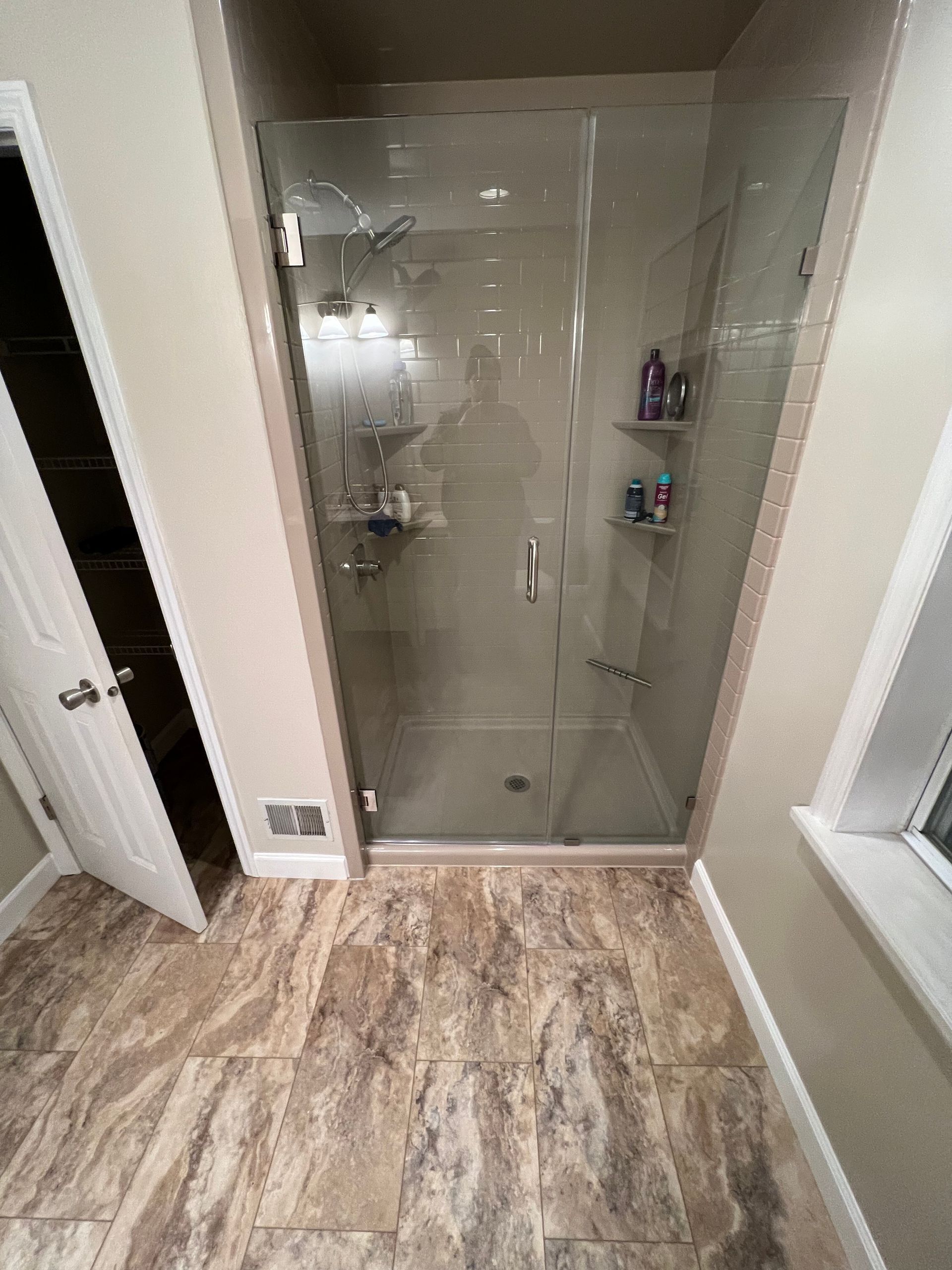 A bathroom with a walk in shower with a glass door.