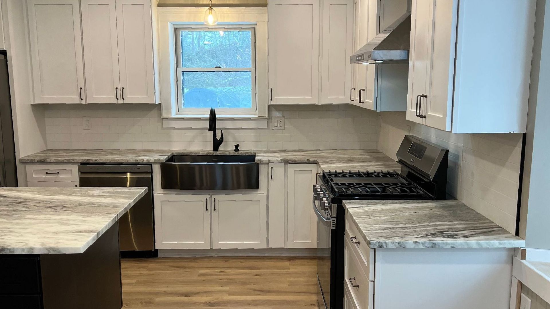 A kitchen with white cabinets , granite counter tops , a stove and a sink.