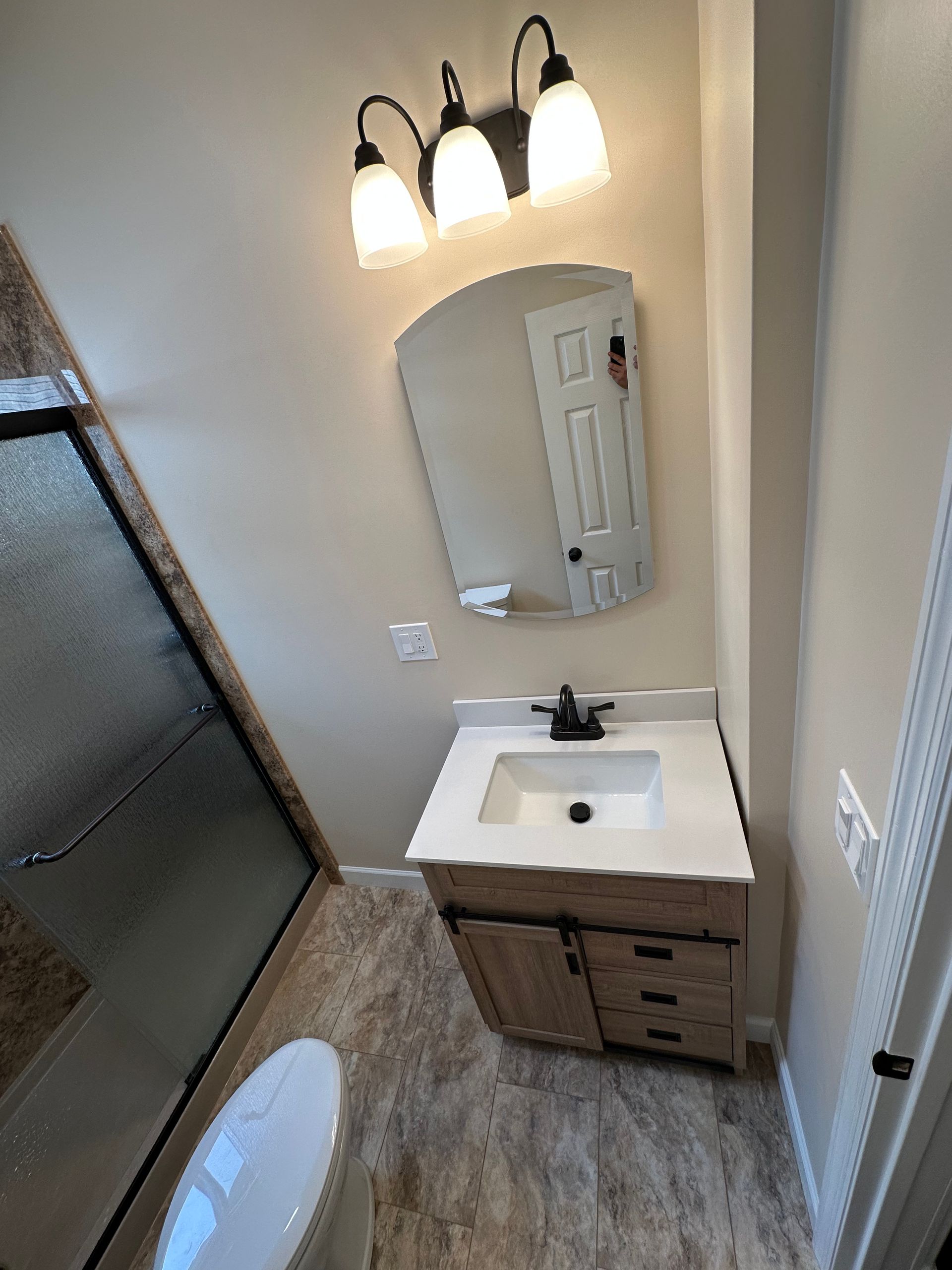 A bathroom with a sink , toilet , mirror and shower.