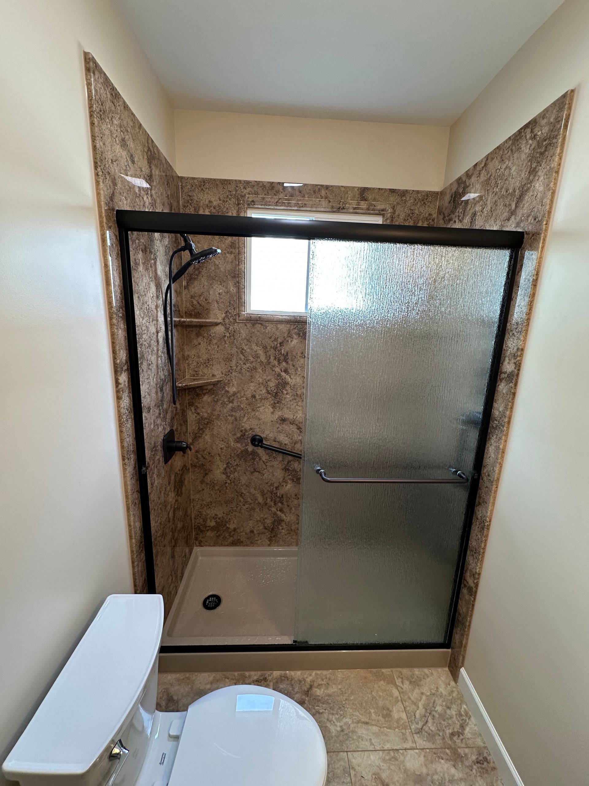 A bathroom with a toilet and a shower with a sliding glass door.