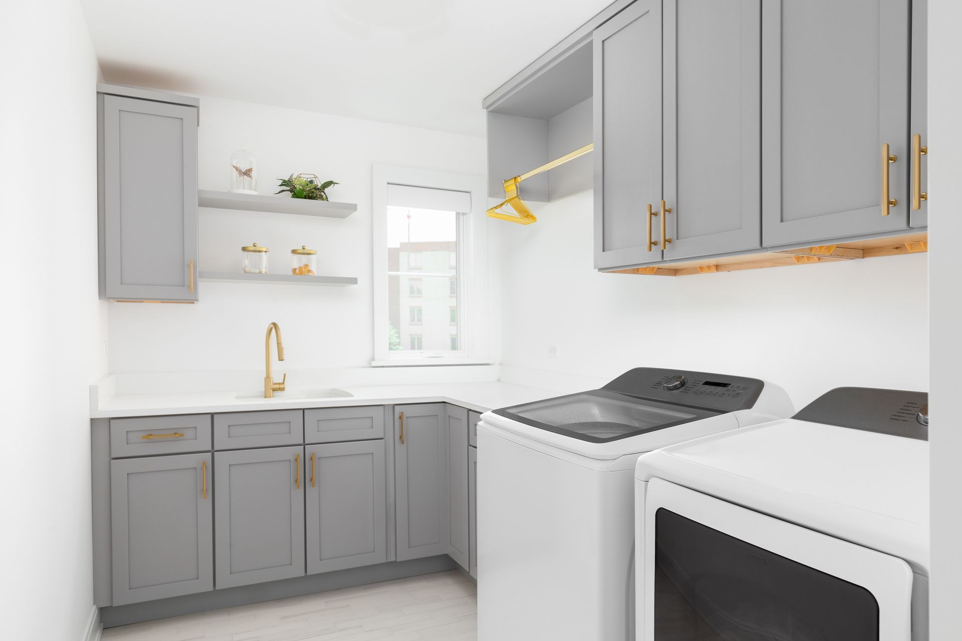 A laundry room with gray cabinets and white appliances.