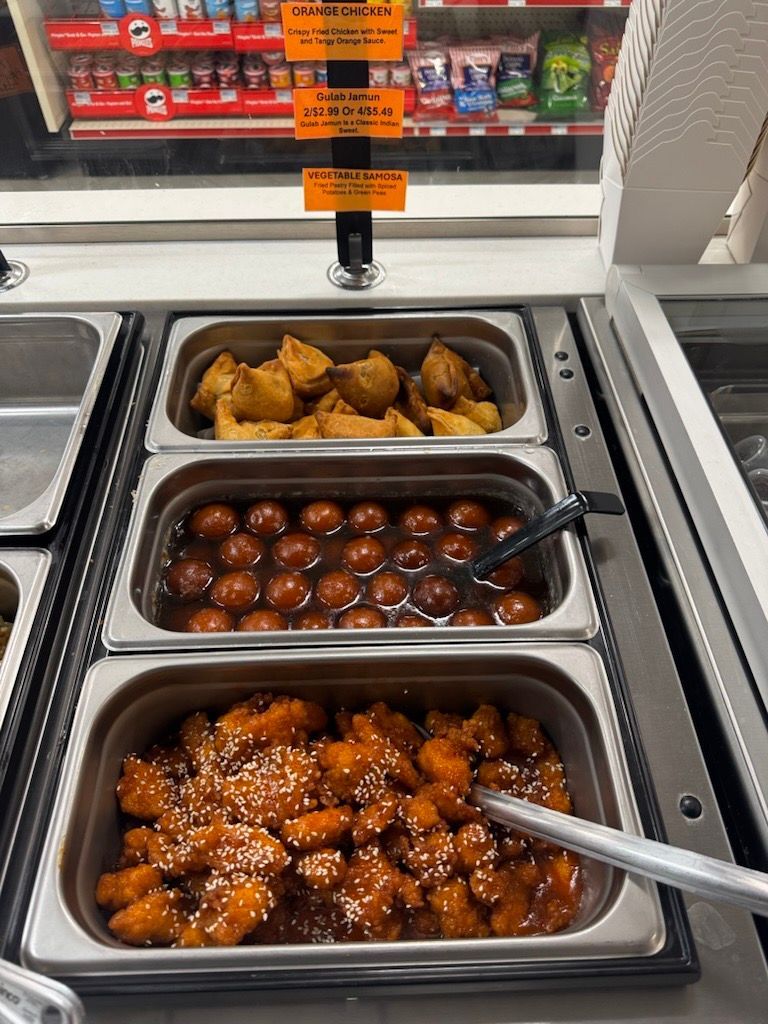 Food buffet with fried items and sweets in a store.