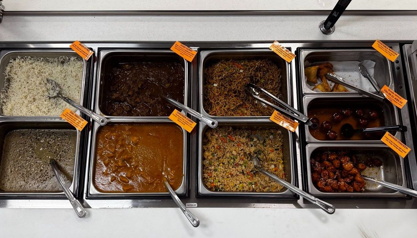 Buffet with various food dishes in stainless steel containers, with serving utensils.
