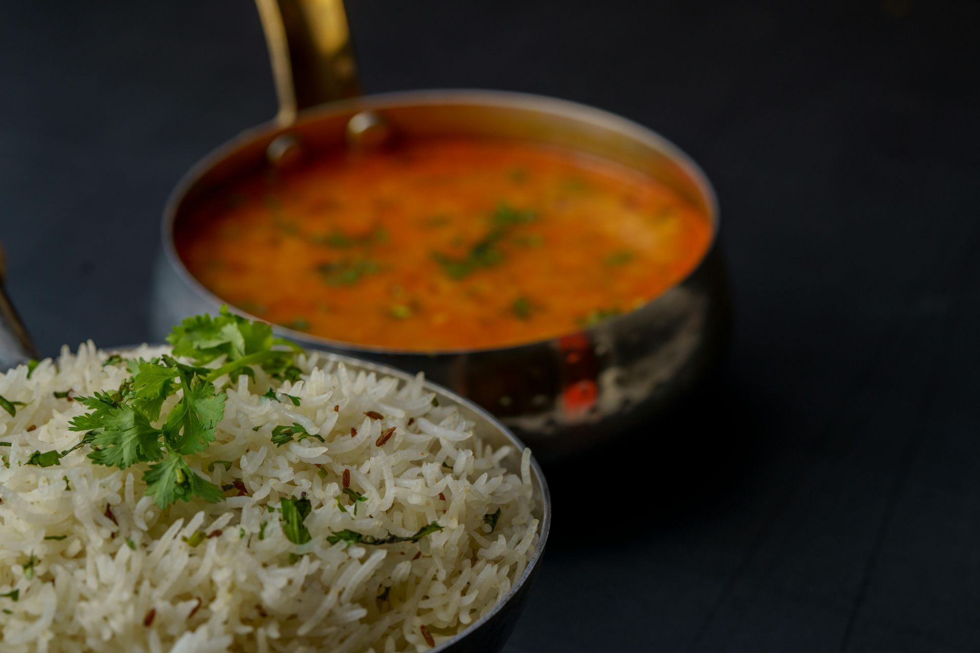Bowl of rice with coriander and bowl of orange-colored lentil soup.
