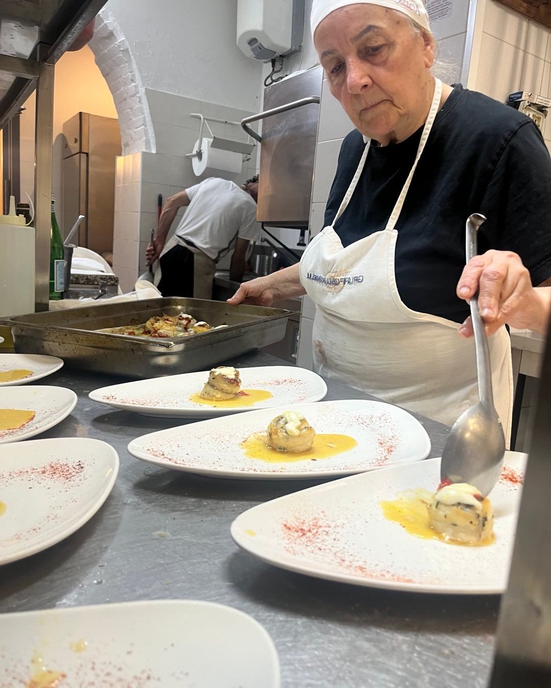 Una donna sta cucinando in cucina con piatti di cibo sul tavolo.