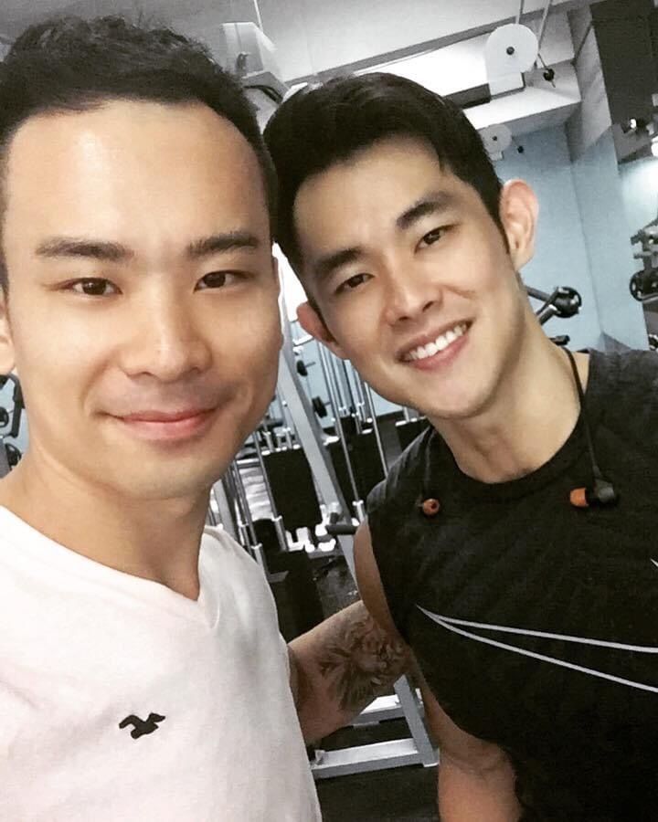 Two men are posing for a picture in a gym.