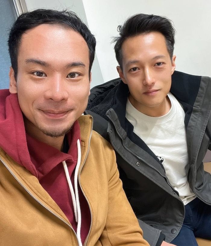 Two men are sitting next to each other and smiling for the camera