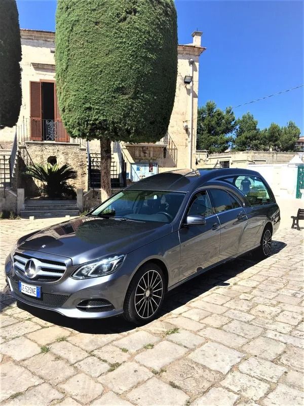 Un'auto funebre mercedes benz è parcheggiata davanti a una casa.