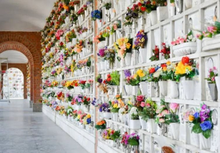 Una fila di scaffali pieni di fiori in vaso in un cimitero.