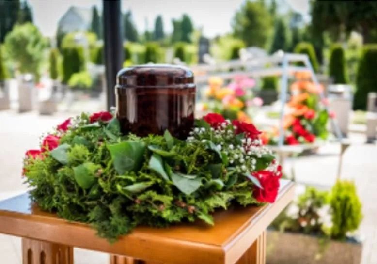 Un'urna è posta sopra un tavolo di legno circondata da fiori.