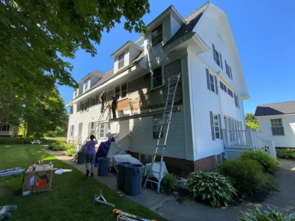 A group of people are working on the side of a house
