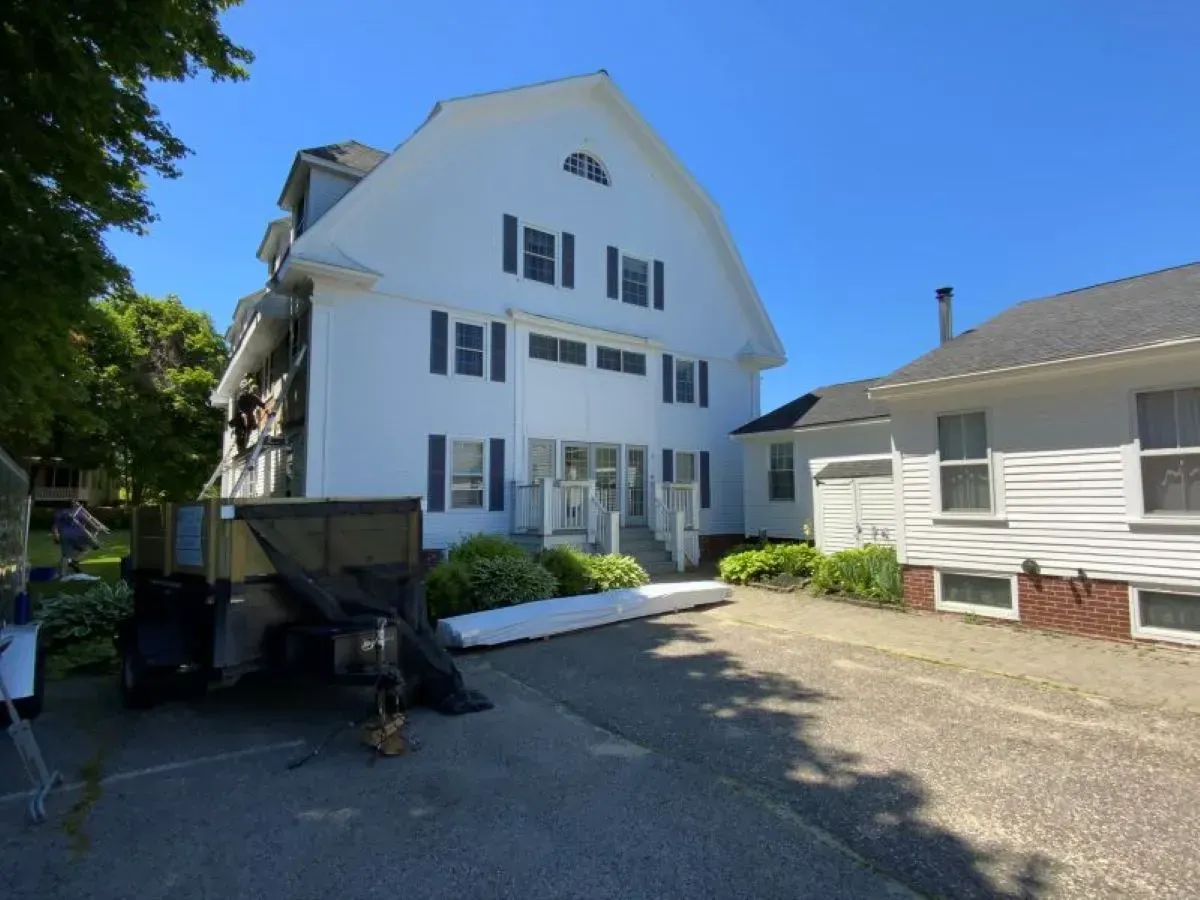 A large white house with a trailer parked in front of it