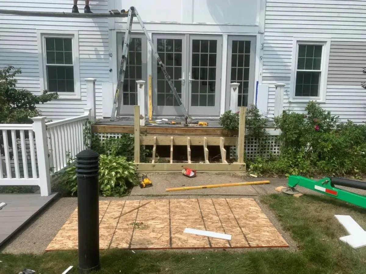 A wooden deck is being built in front of a white house.