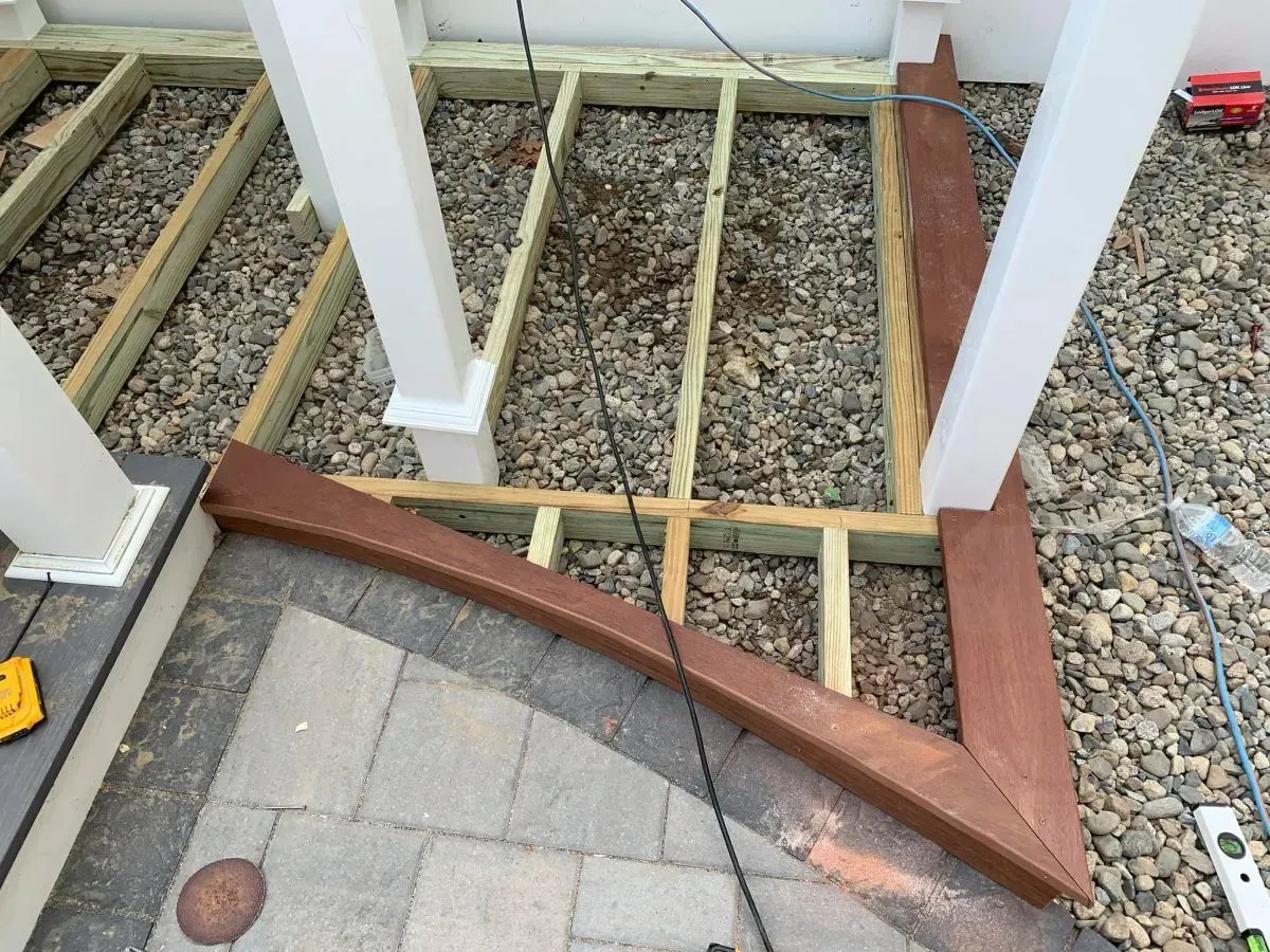 A wooden deck is being built on a gravel ground