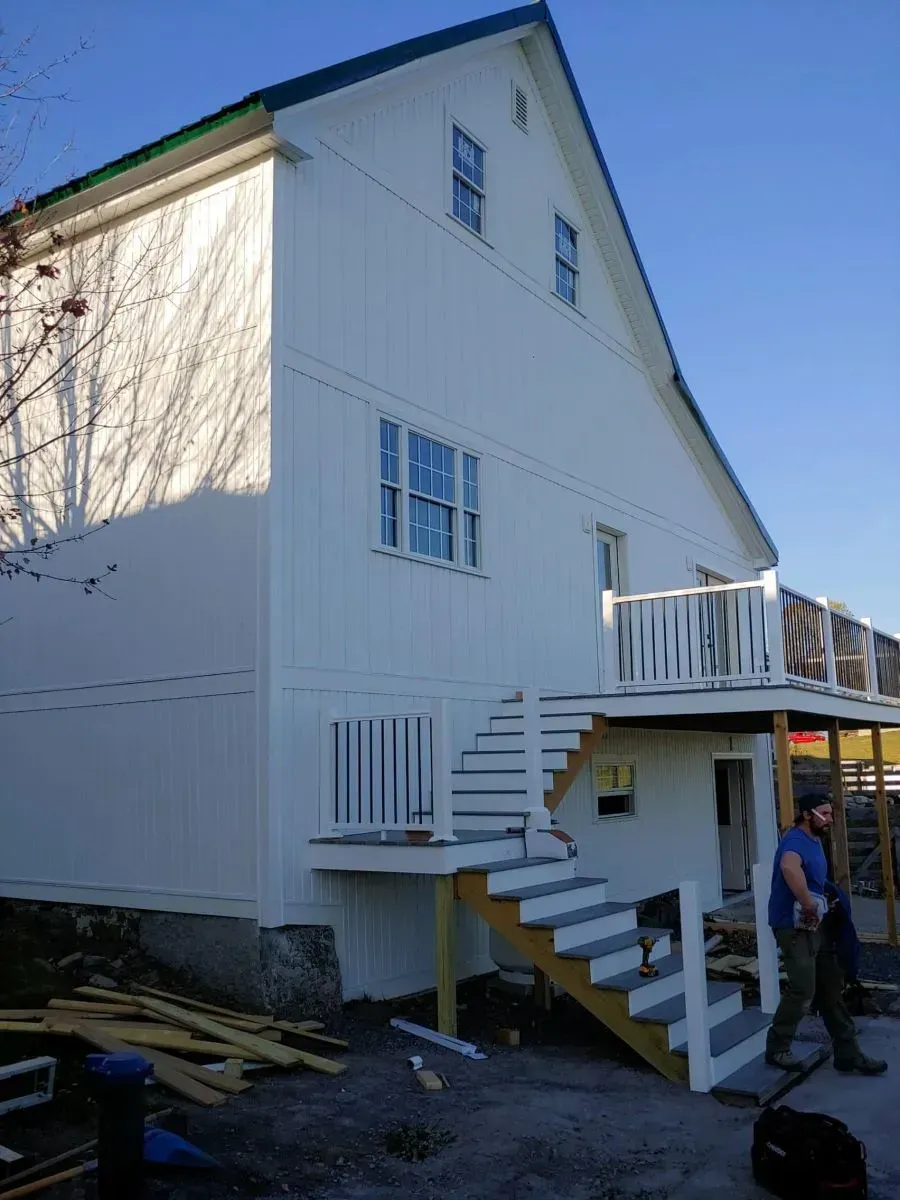A white house with stairs leading up to a deck