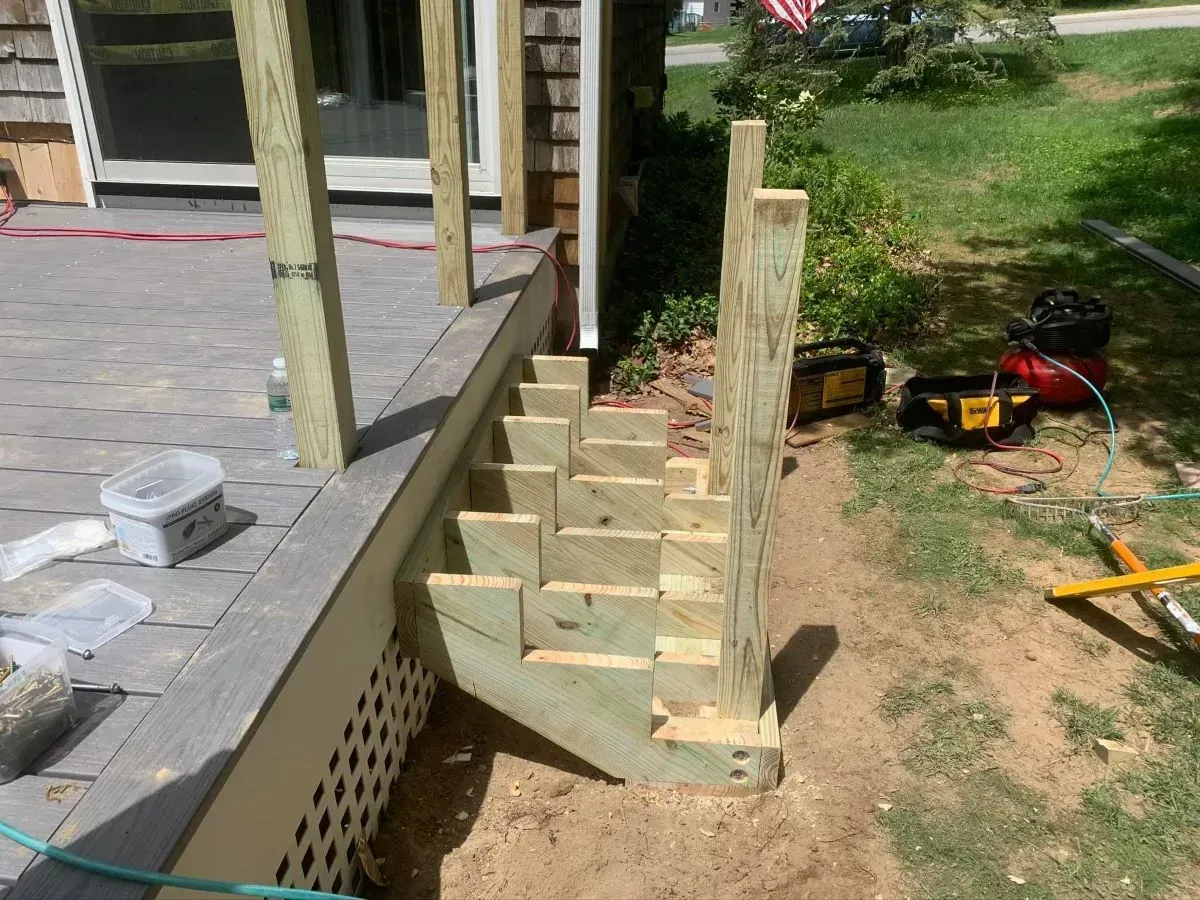 A wooden staircase is being built on the side of a house