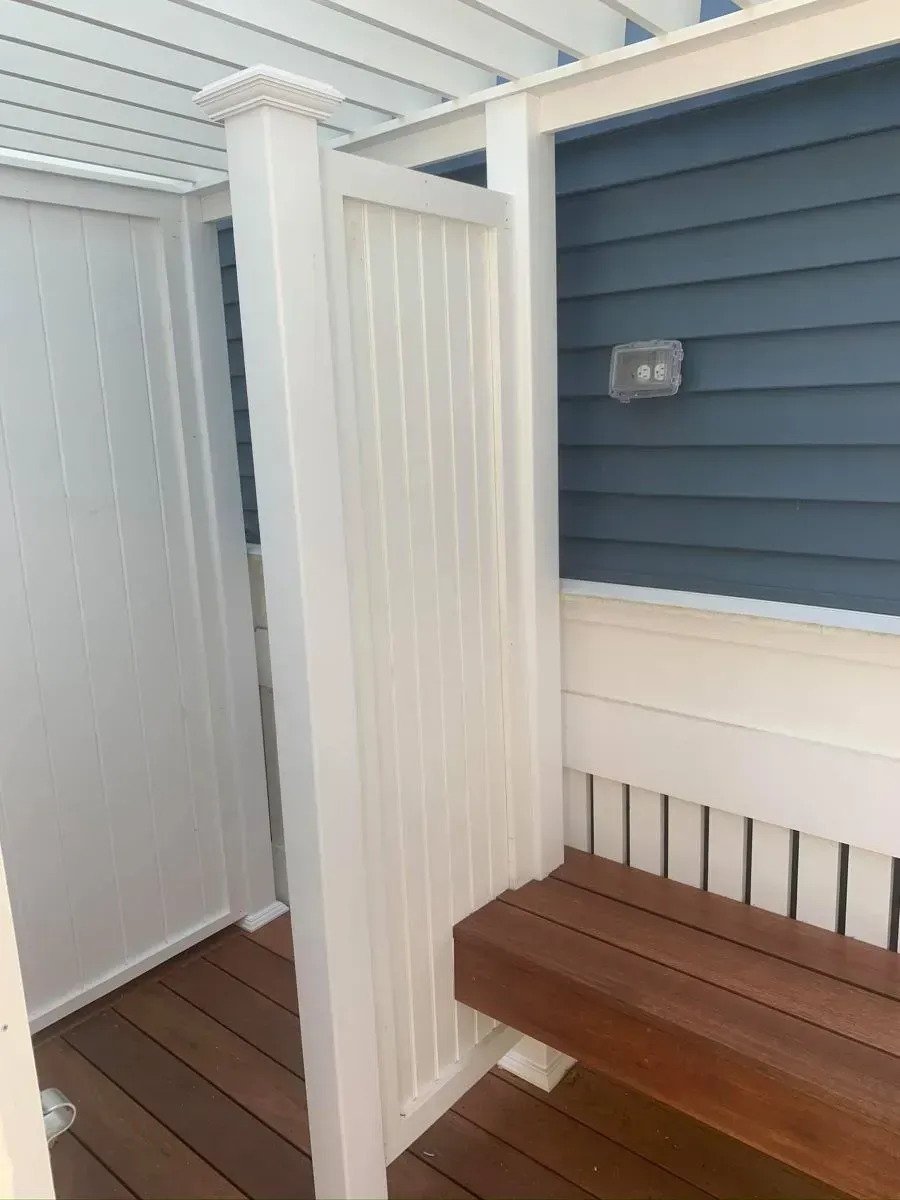 A white fence with a wooden bench in front of it